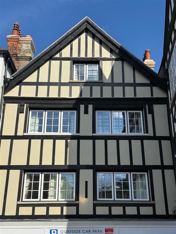 Gable end of Basing House showing multiple new white-framed timber windows and chimneys
