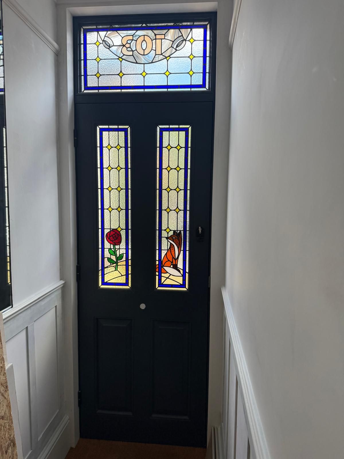 Interior view of navy entrance door with fox and rose stained glass panels