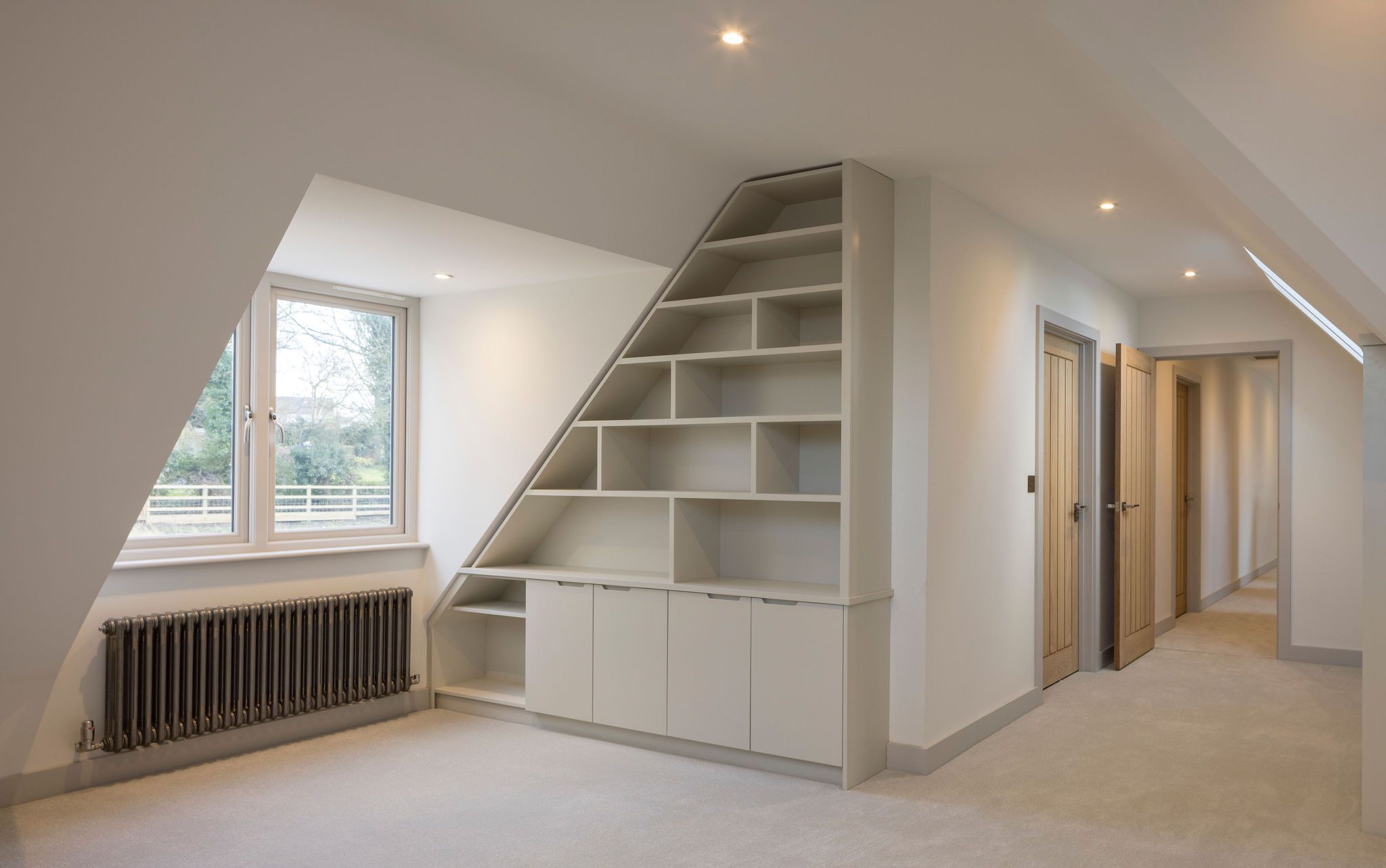 Bespoke fitted shelving and storage cupboards built into loft eaves