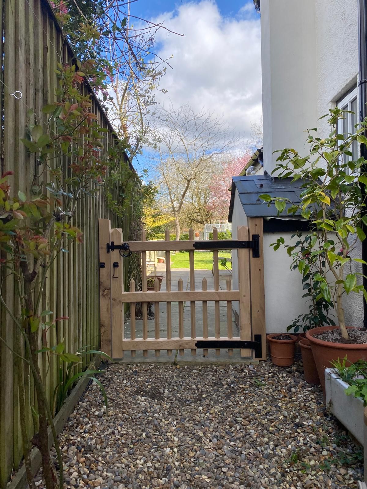 Bespoke oak picket garden gate leading to a courtyard patio