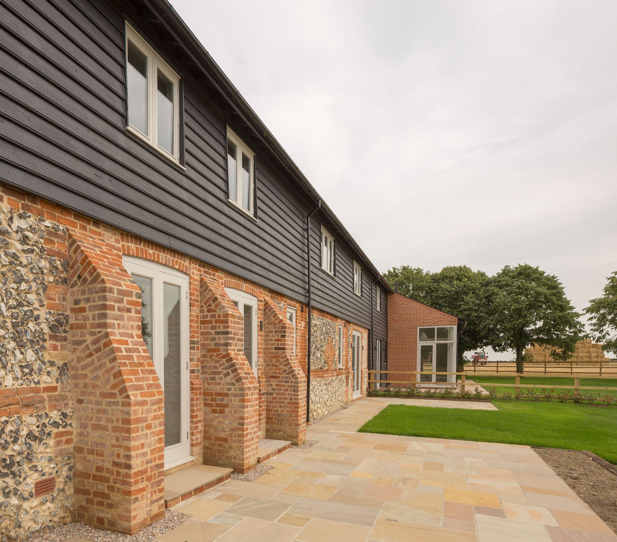 Row of timber French doors set into flint and brick barn courtyard wall