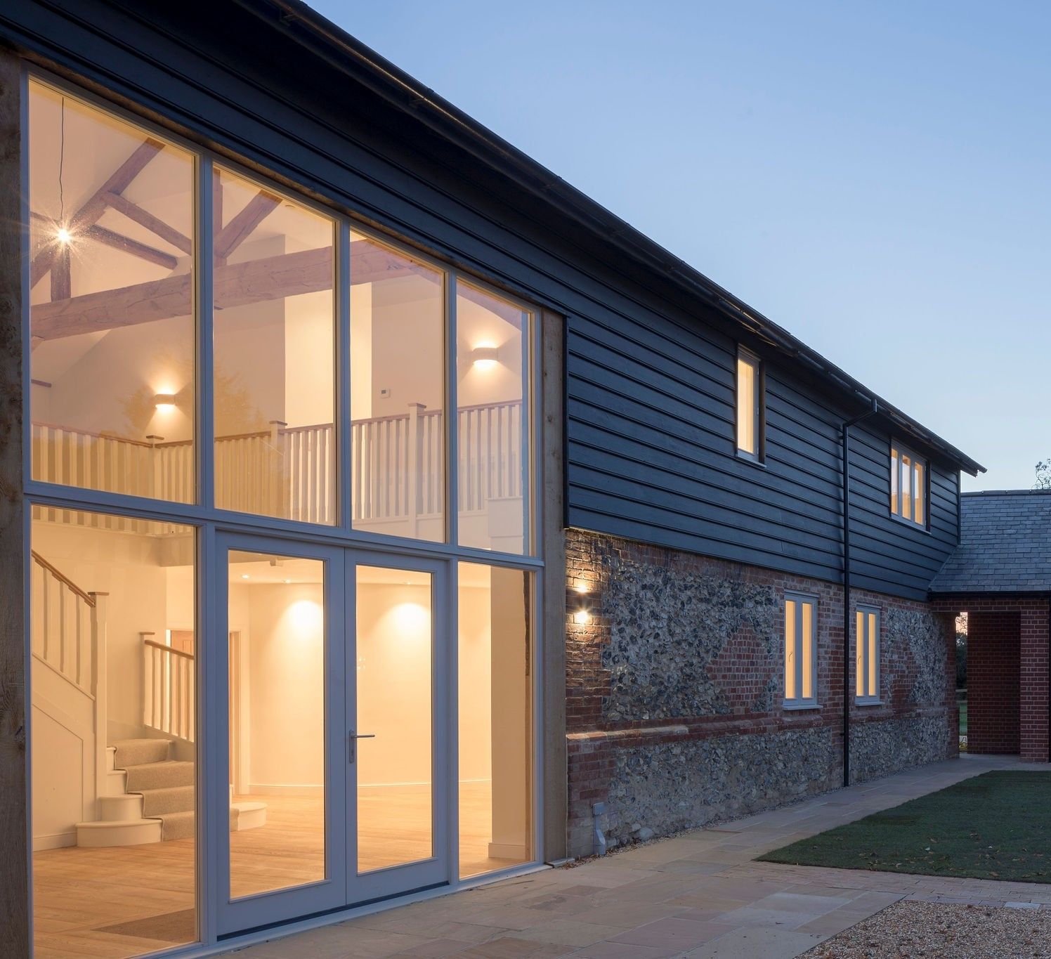 Barn conversion glazed gable entrance illuminated at dusk, thumbnail crop