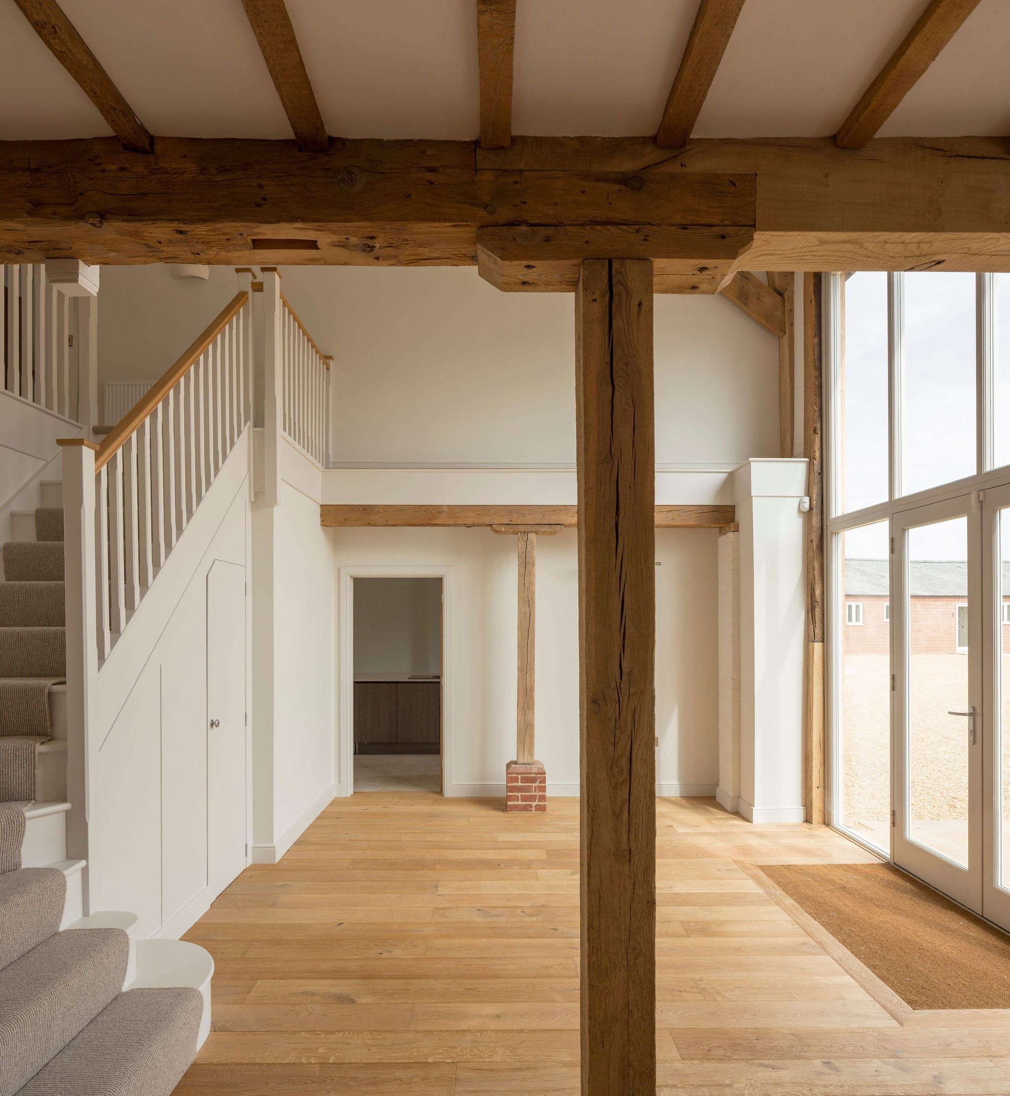 Open-plan interior with exposed oak beams and full-height glazed timber doors
