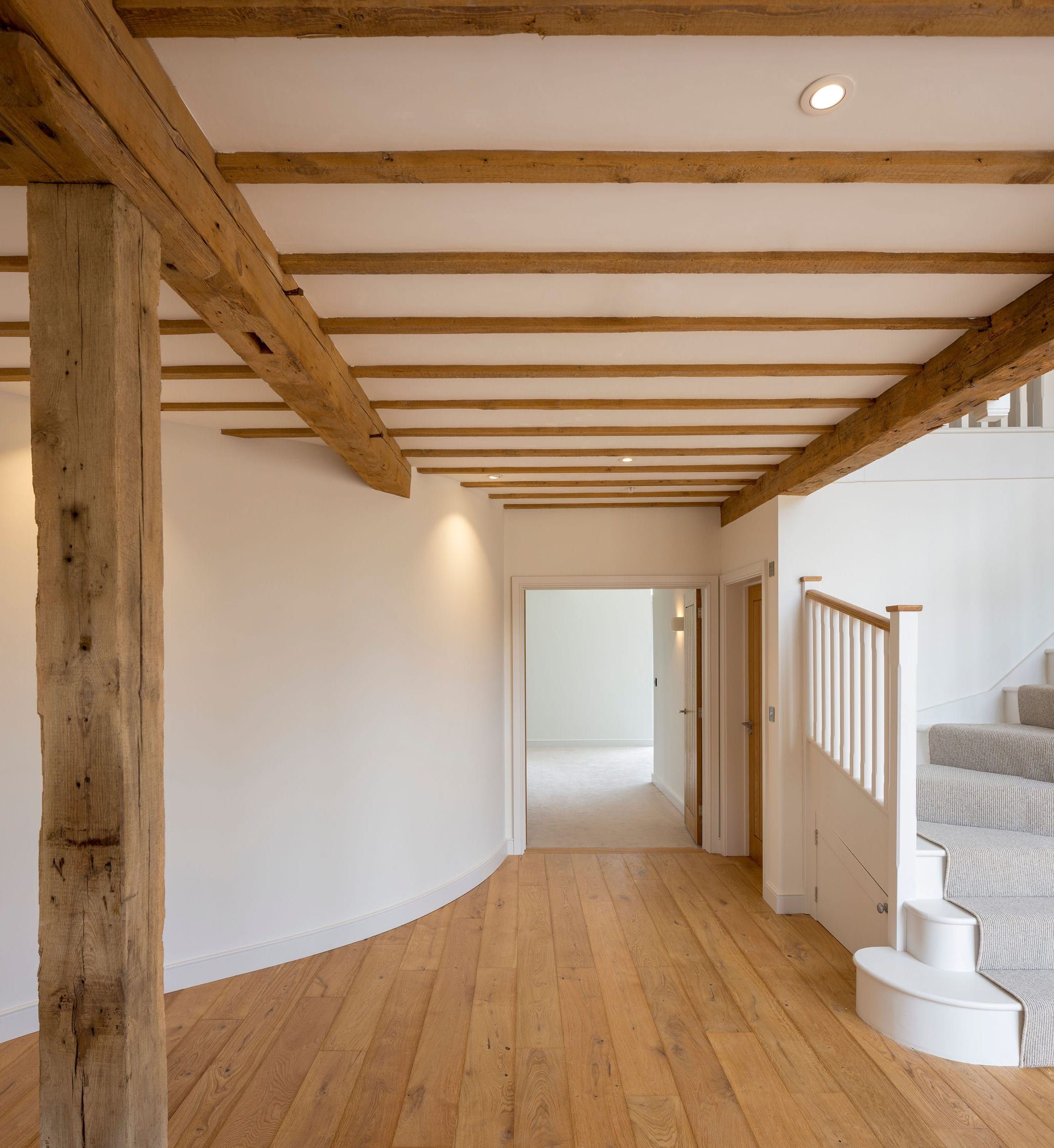 Interior hallway with exposed oak ceiling beams leading to staircase