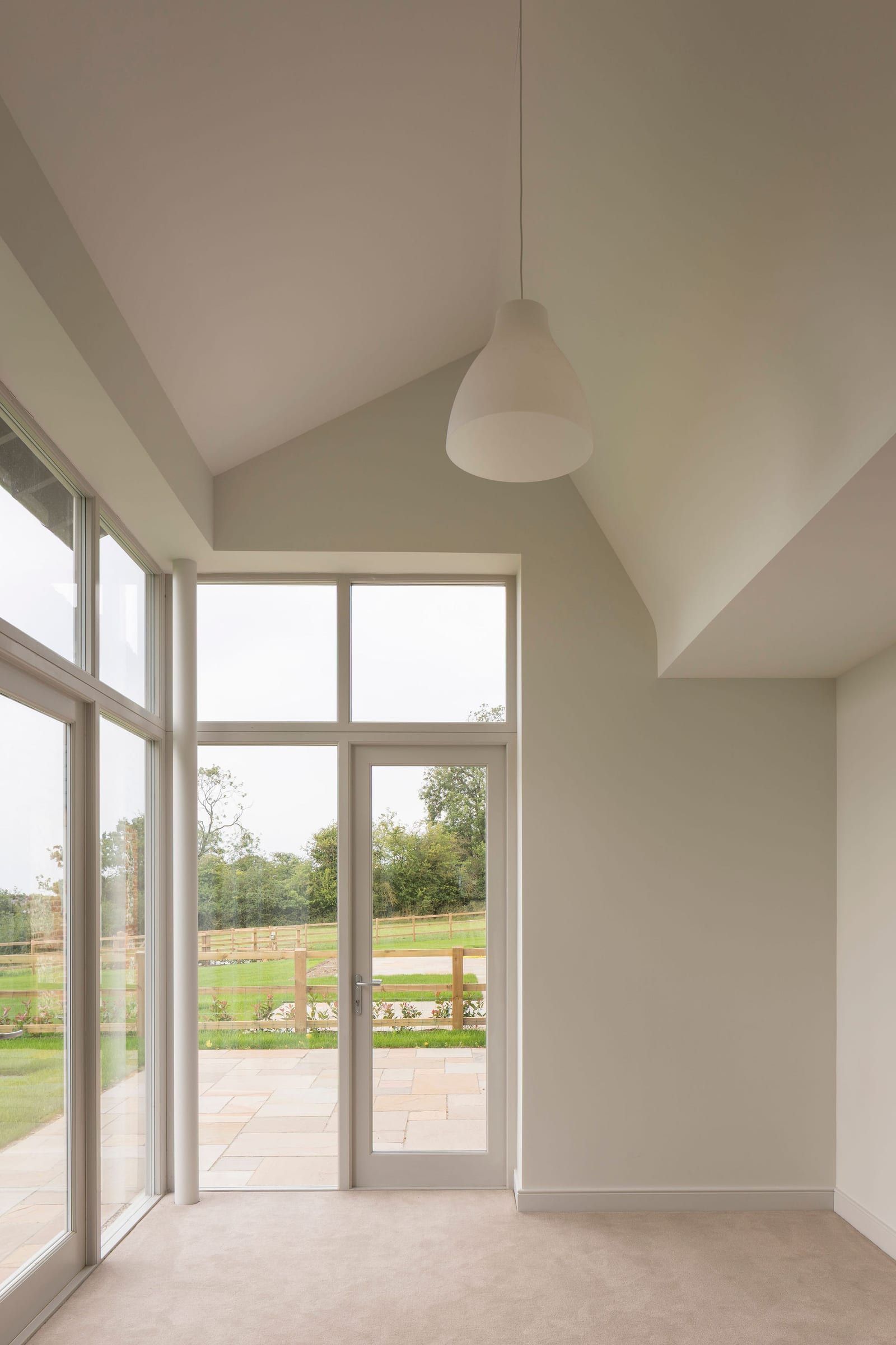 Vaulted interior room with tall timber windows and French door to patio