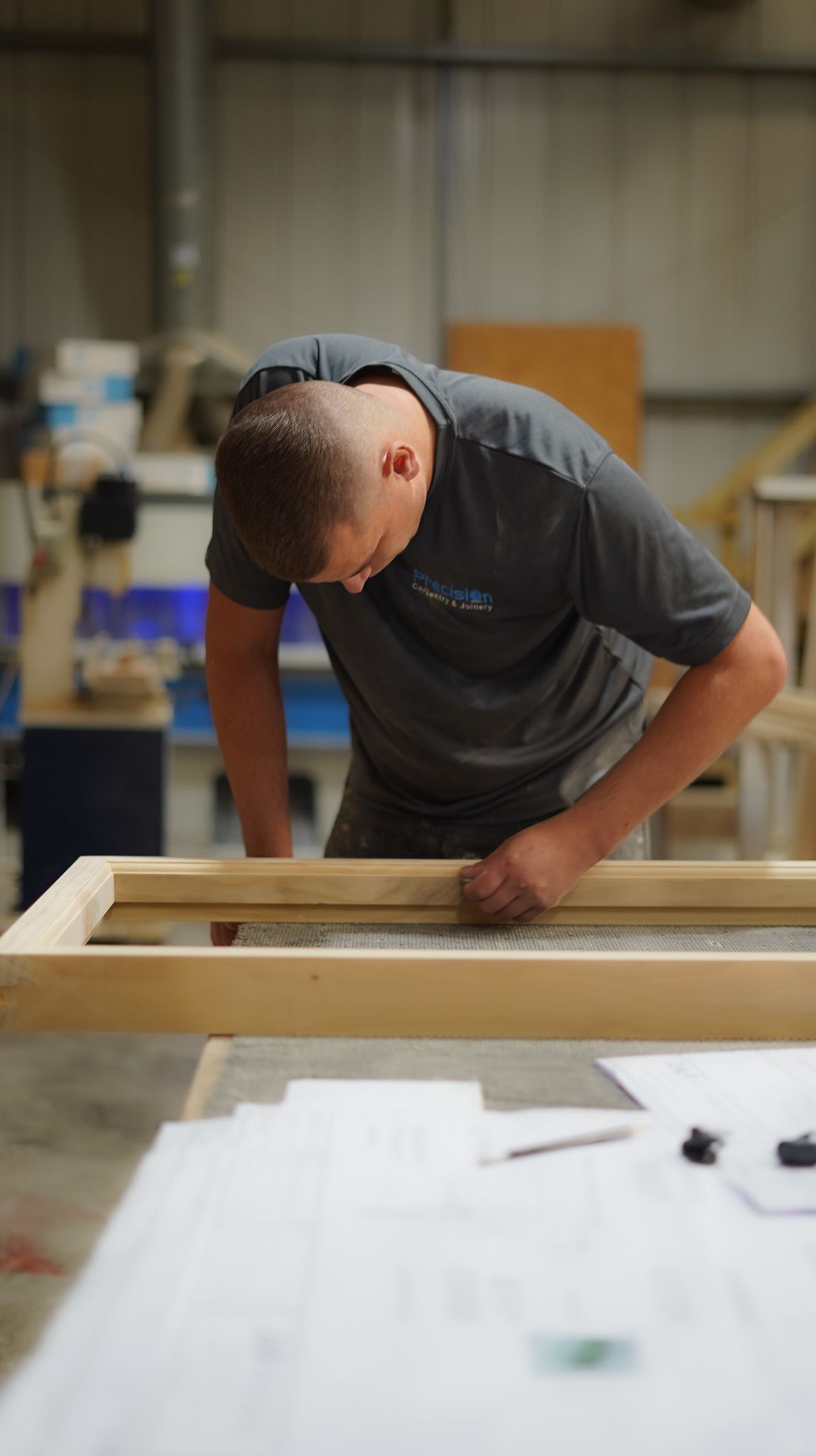 Joiner in workshop assembling a timber window or door frame