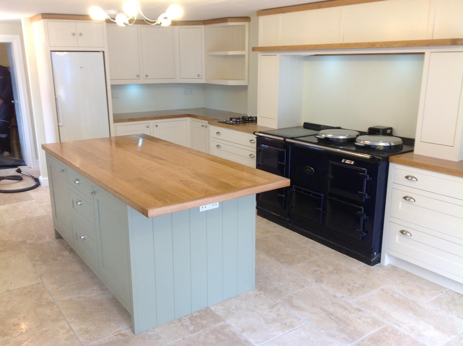 Cream shaker kitchen with oak-topped island and fitted navy Aga range cooker in alcove