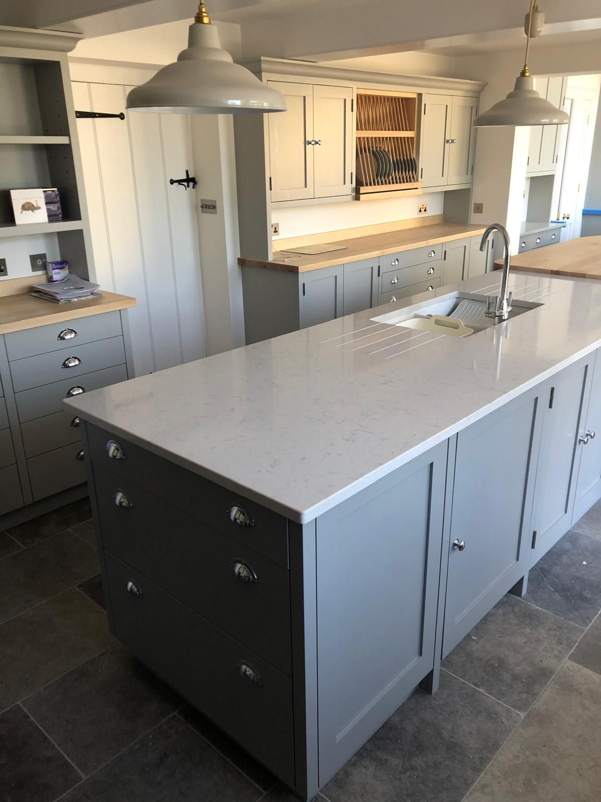 Grey shaker kitchen island with white quartz worktop, inset sink and built-in plate rack cabinet