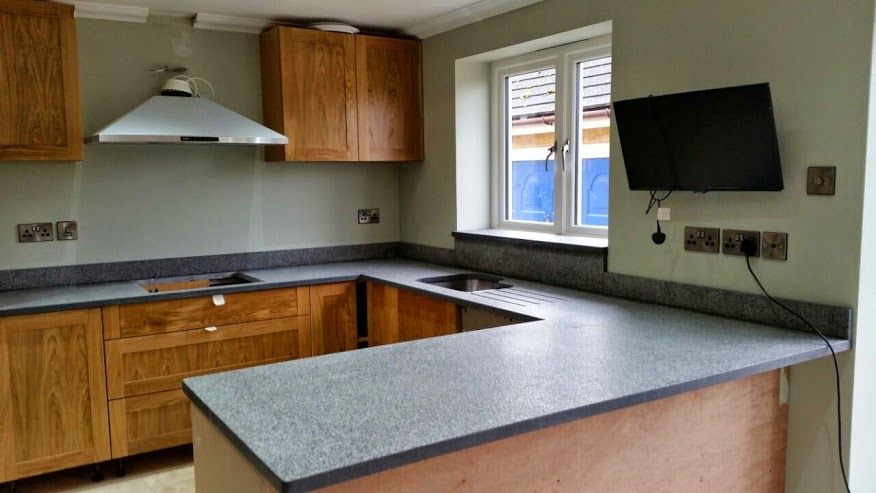 U-shaped oak kitchen cabinetry with speckled grey granite worktop and extractor hood