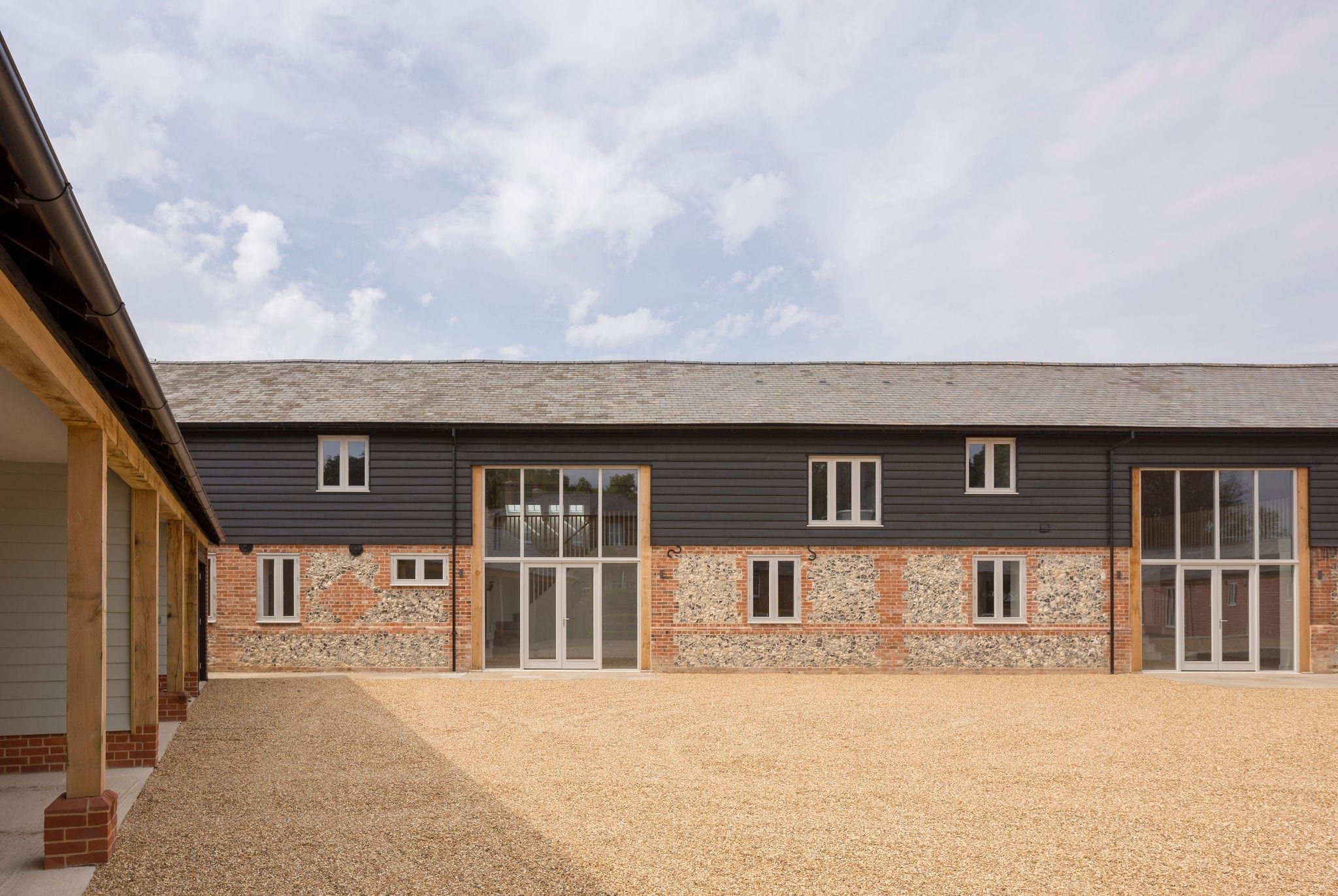Daytime courtyard view of timber French doors and windows in barn facade