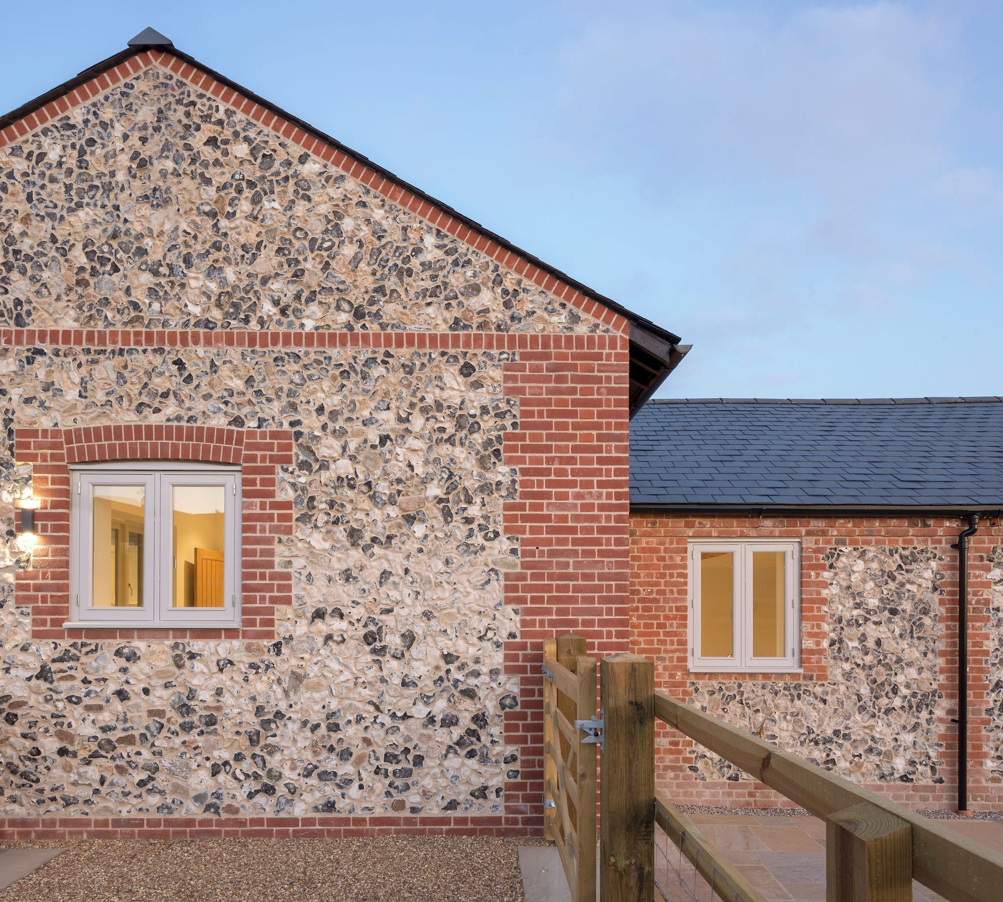 Close-up of flint gable wall with timber casement windows at dusk