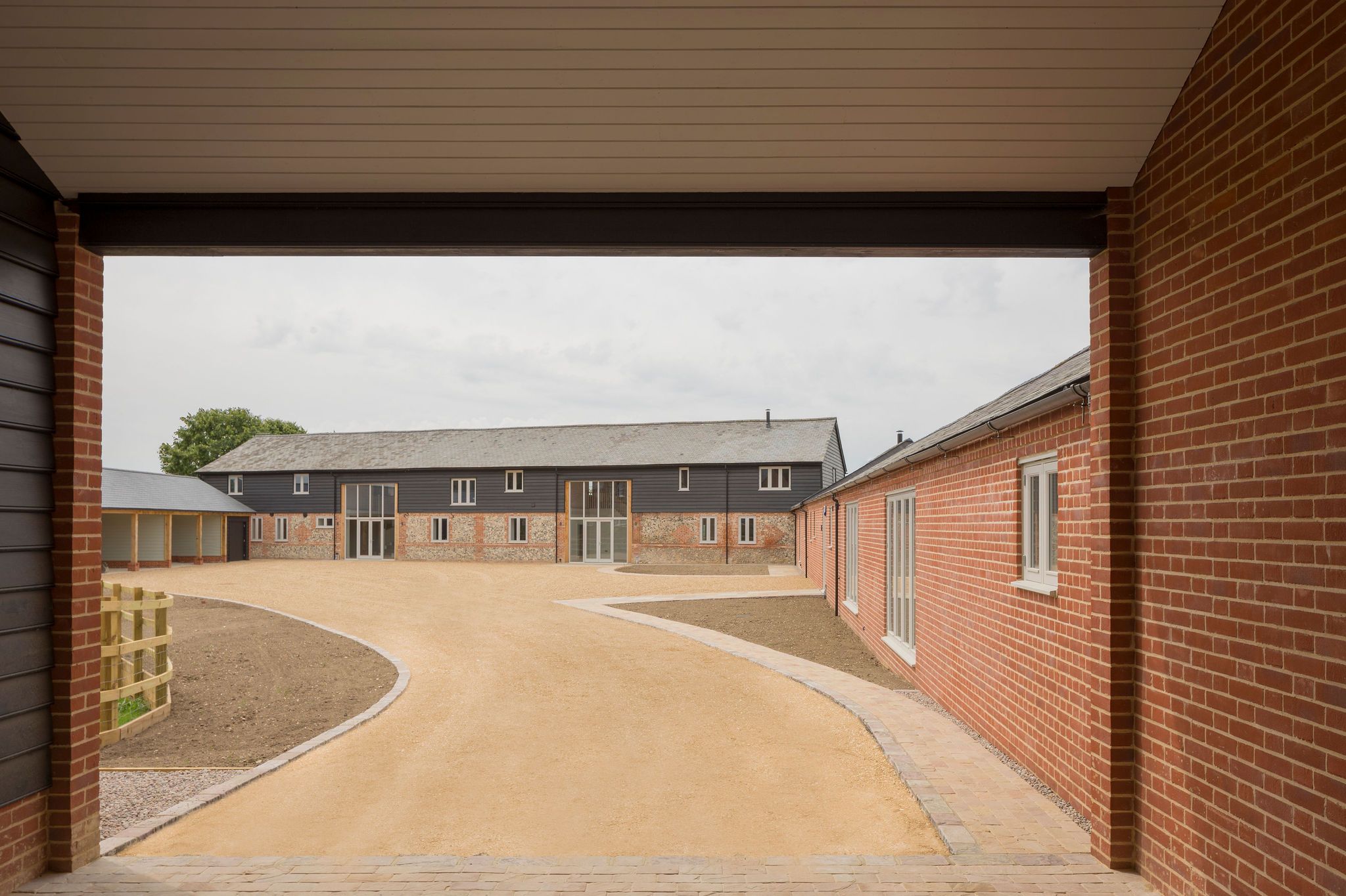 View through brick breezeway across courtyard to converted barn
