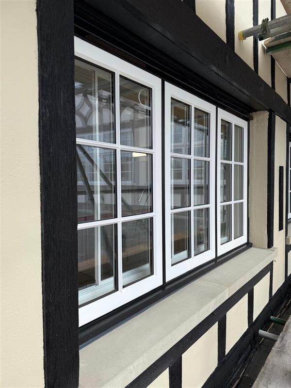 Close-up of a new white Accoya timber window installed in the black-and-white timber-framed wall
