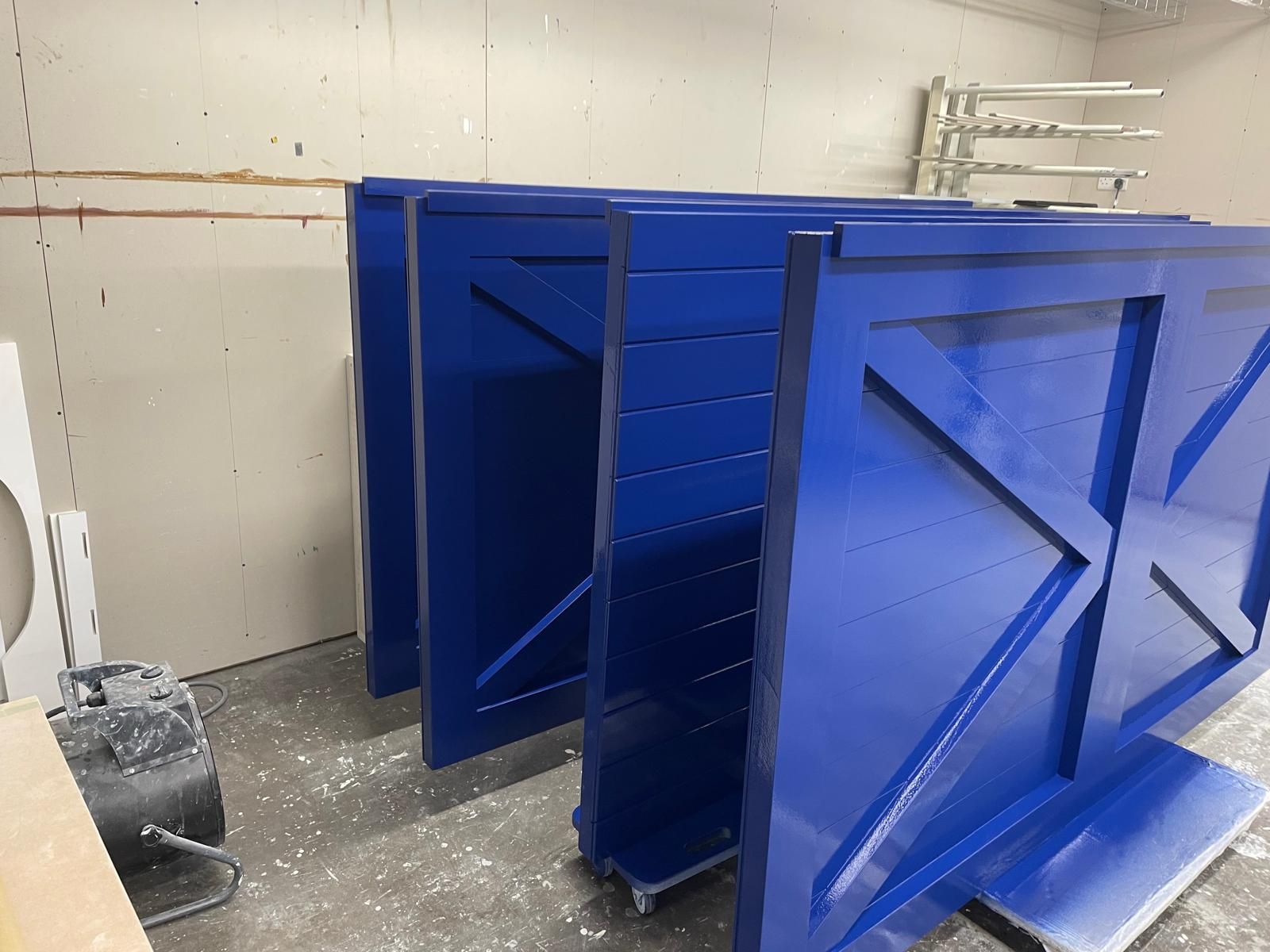 Row of glossy blue ledge-and-brace timber doors freshly spray finished