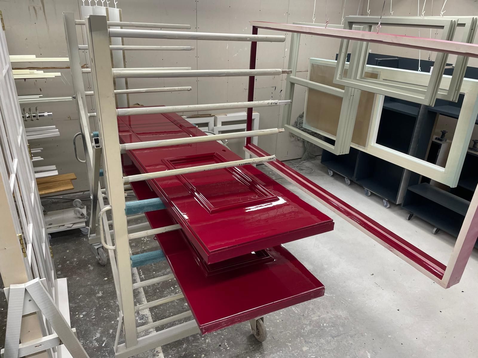 Gloss red spray-finished doors on a rack among other painted joinery items