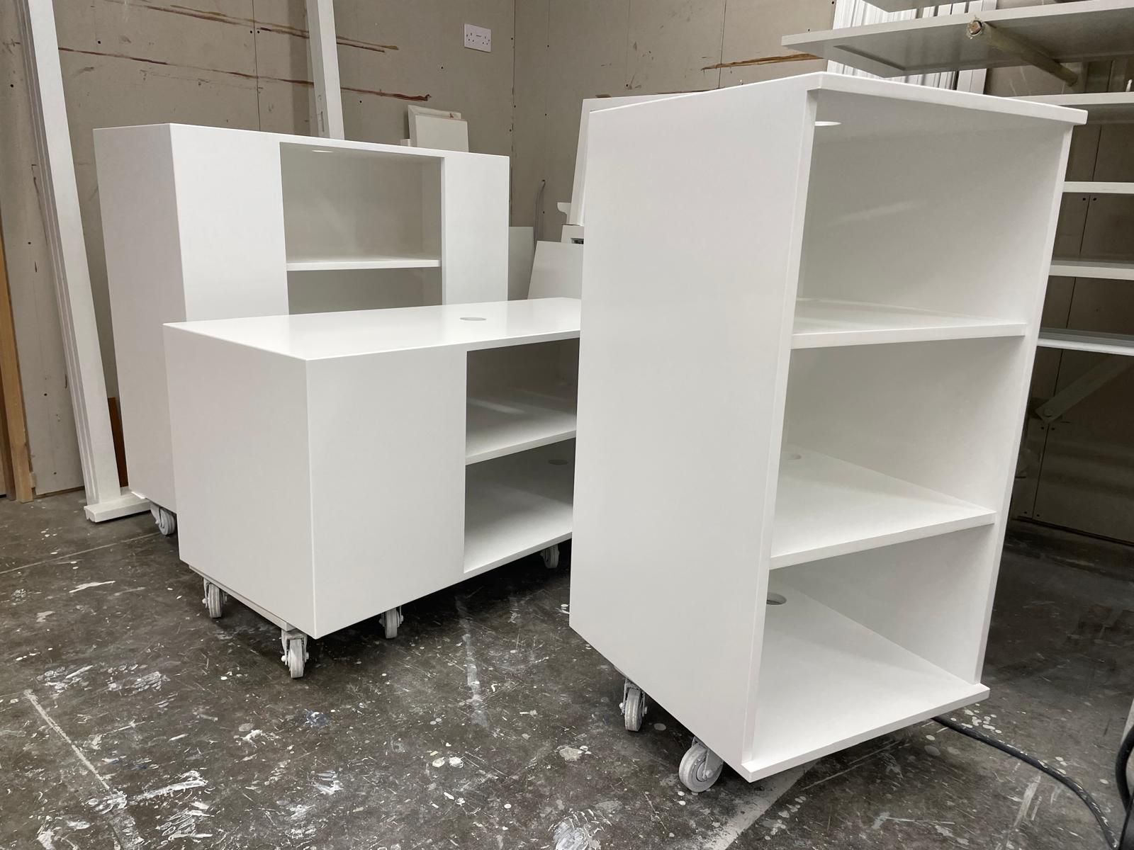 White sprayed kitchen cabinet carcasses on castors in the finishing workshop