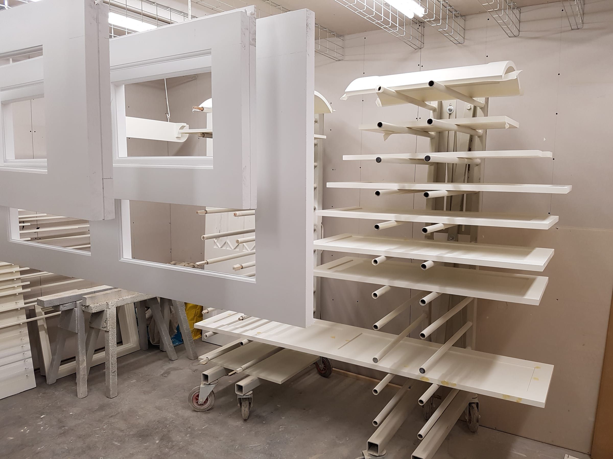 Freshly sprayed white timber sash windows resting on a workshop drying rack