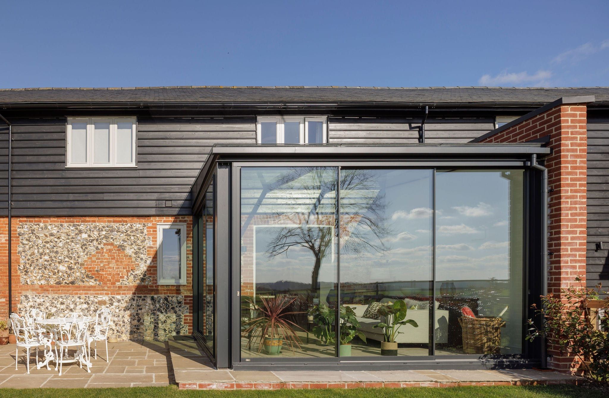 Dark-framed glazed sliding doors on garden room extension of converted barn