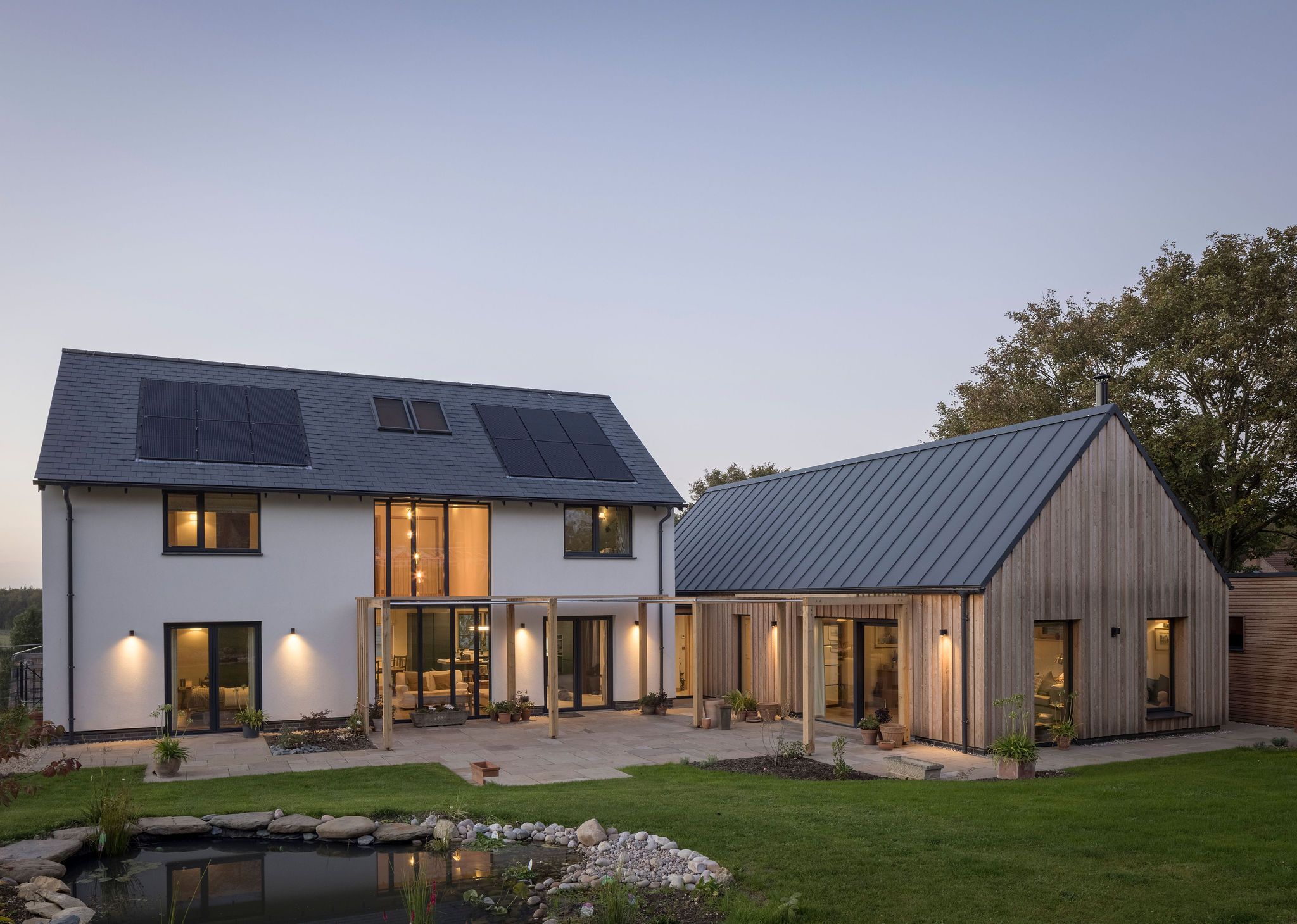 Contemporary self-build home at dusk with glazed bifold doors lit along the rear