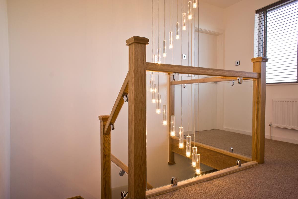 Oak-framed glass balustrade on a staircase landing with pendant lights