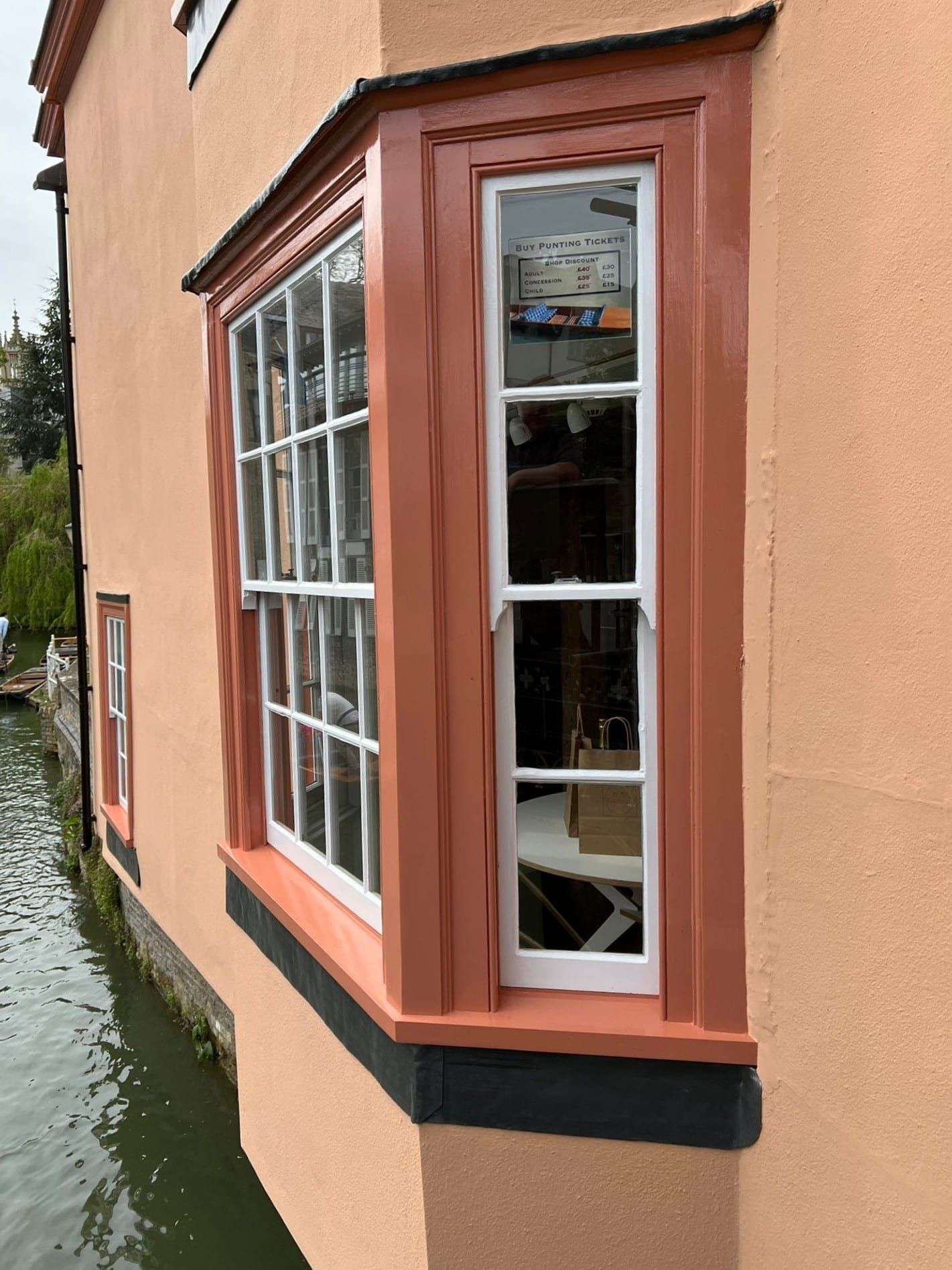 Close-up of a traditional terracotta-painted timber box sash window by a river