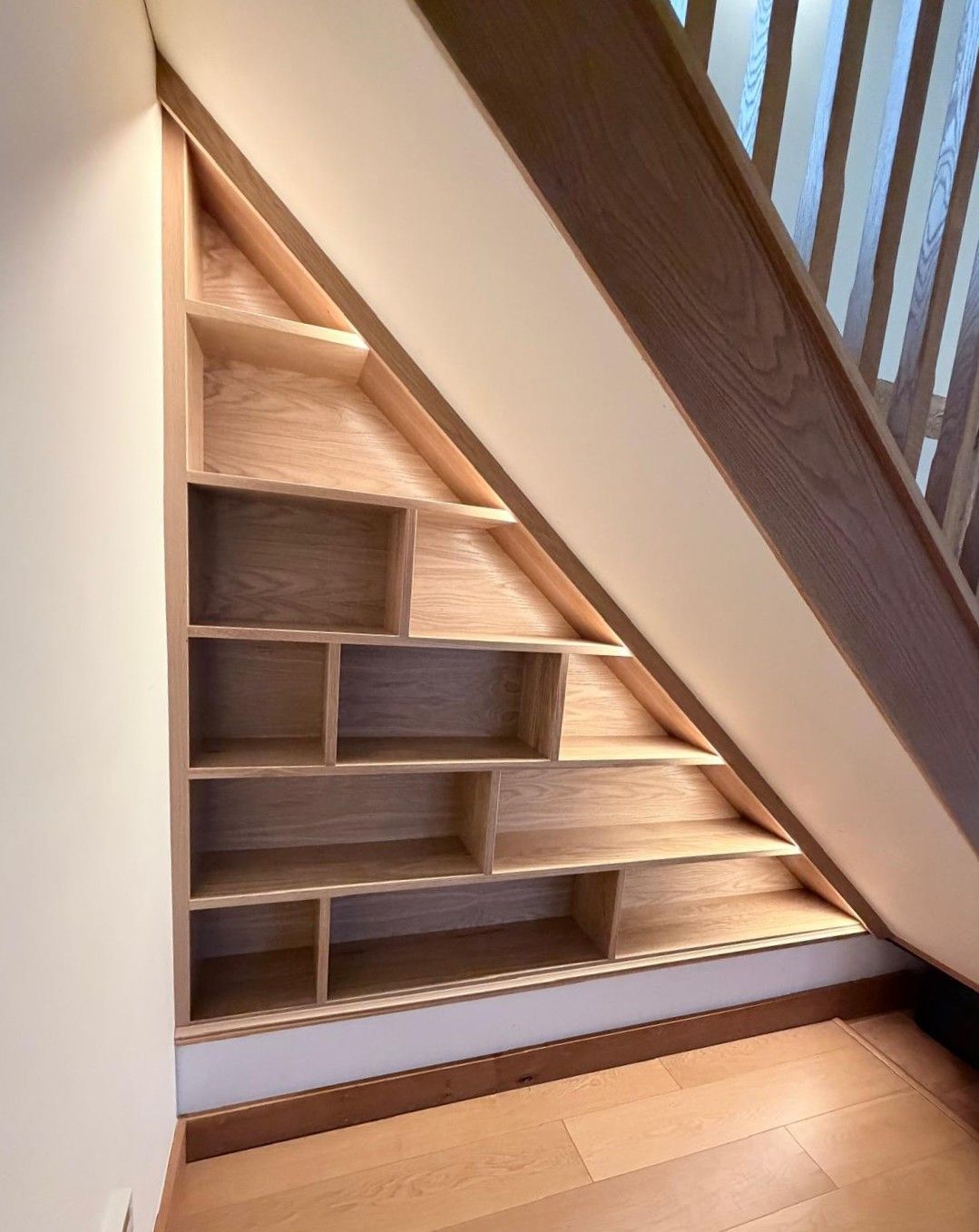 Empty triangular oak understairs shelving unit viewed straight on