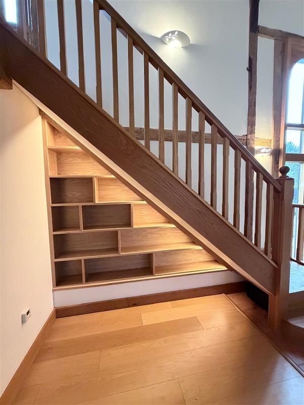 Close-up view of triangular oak understairs shelving with warm integrated lighting