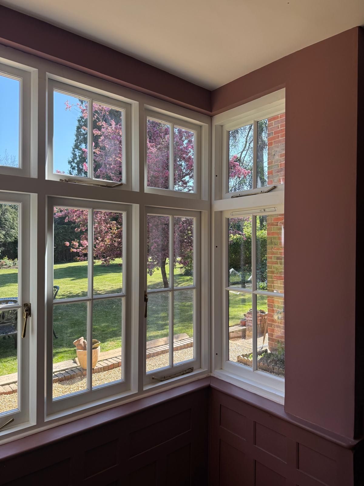Interior view through slim white timber vacuum glass windows overlooking garden