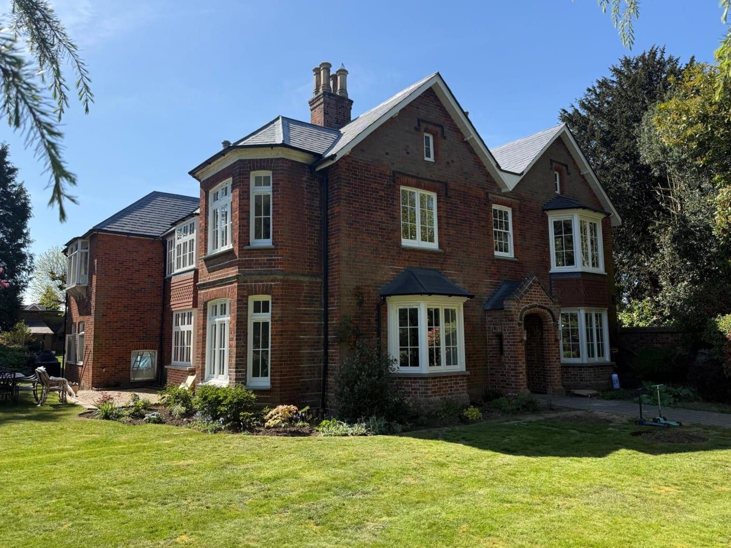 Red-brick period house with white timber bay windows fitted with vacuum glass