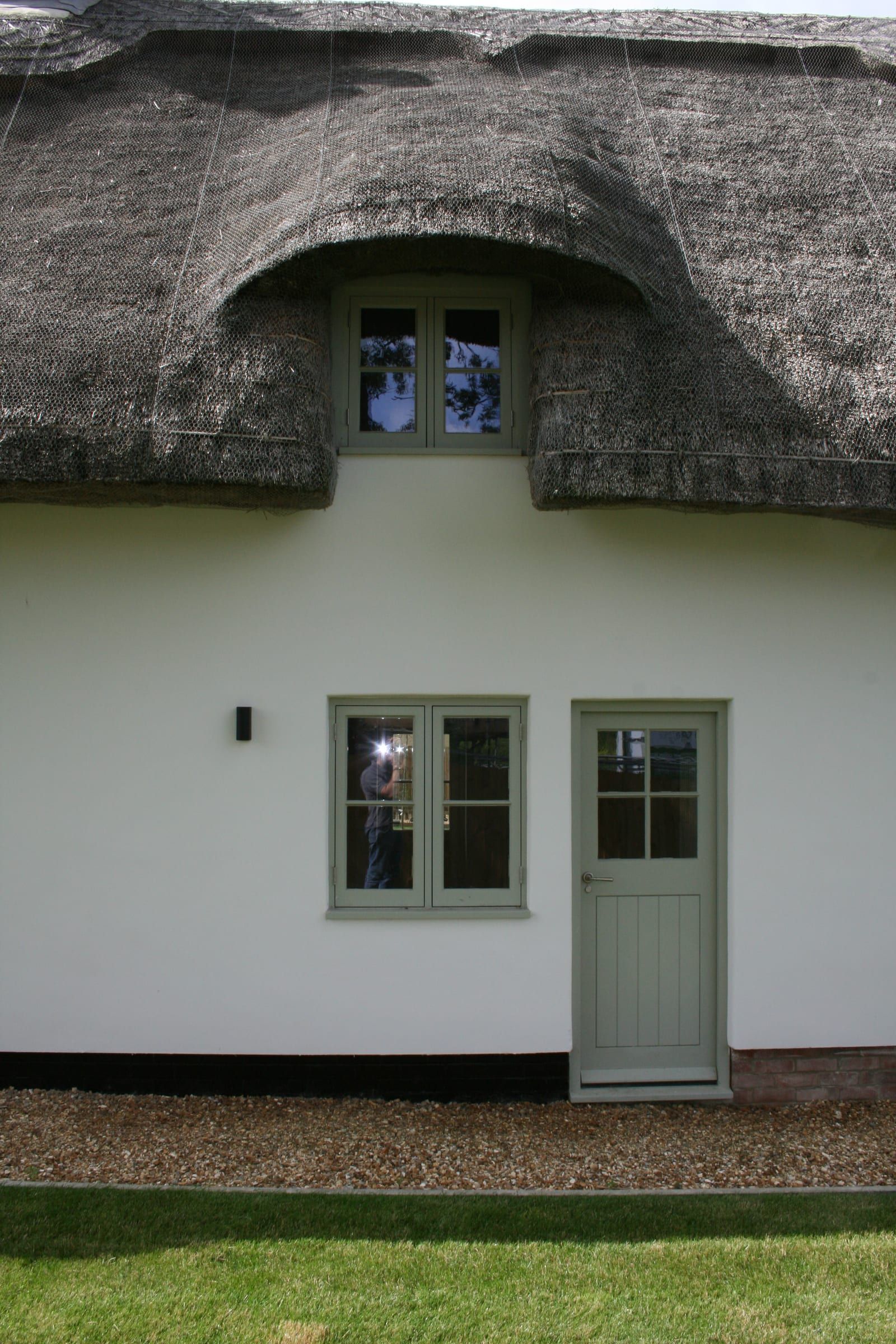 Thatched eyebrow dormer with vacuum glass window above sage-green stable door