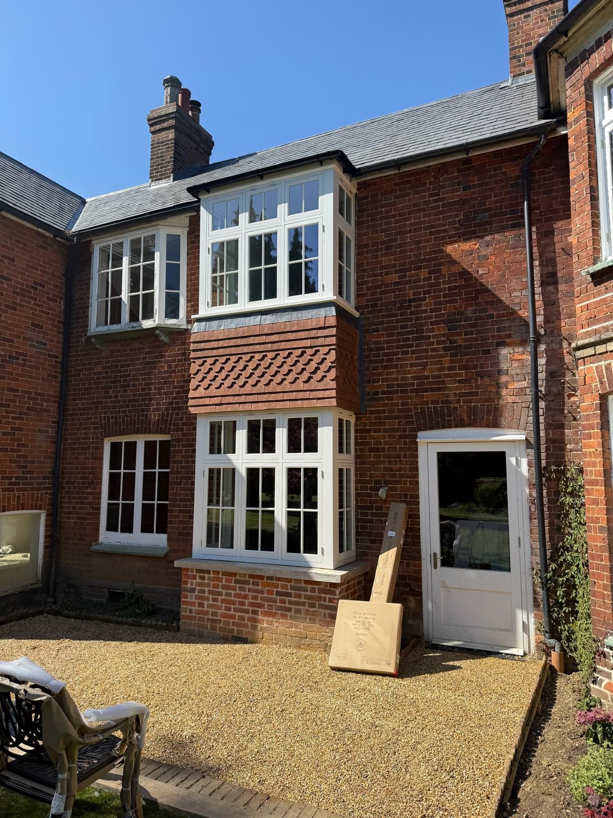 White timber bay windows with vacuum glass on tile-hung brick house gable