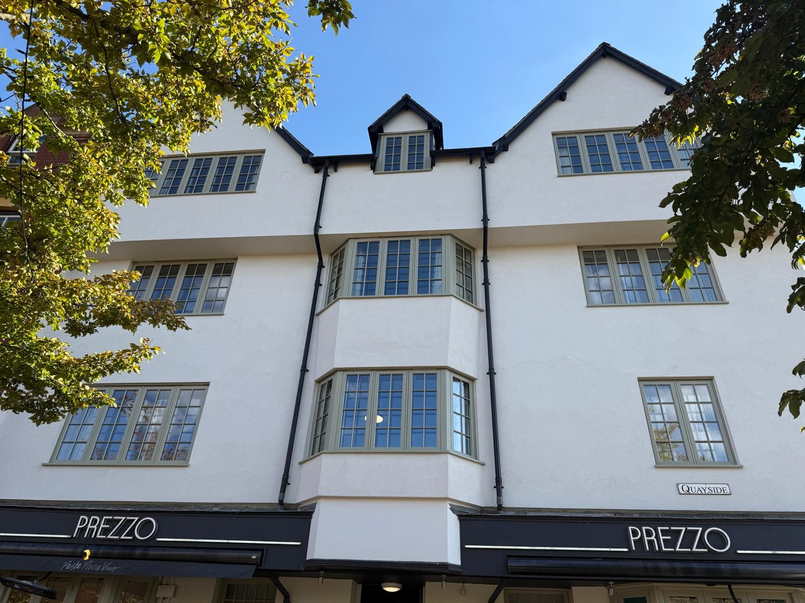 Period building facade with multiple sage-green painted timber casement windows